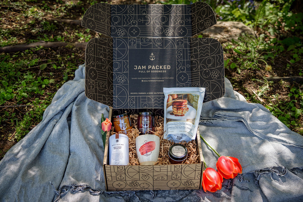 SaltSpring Kitchen Company Limited Edition Mother's Day Gift Boxes_Tumbler and pancakes box open on a picnic blanket with jams and tea