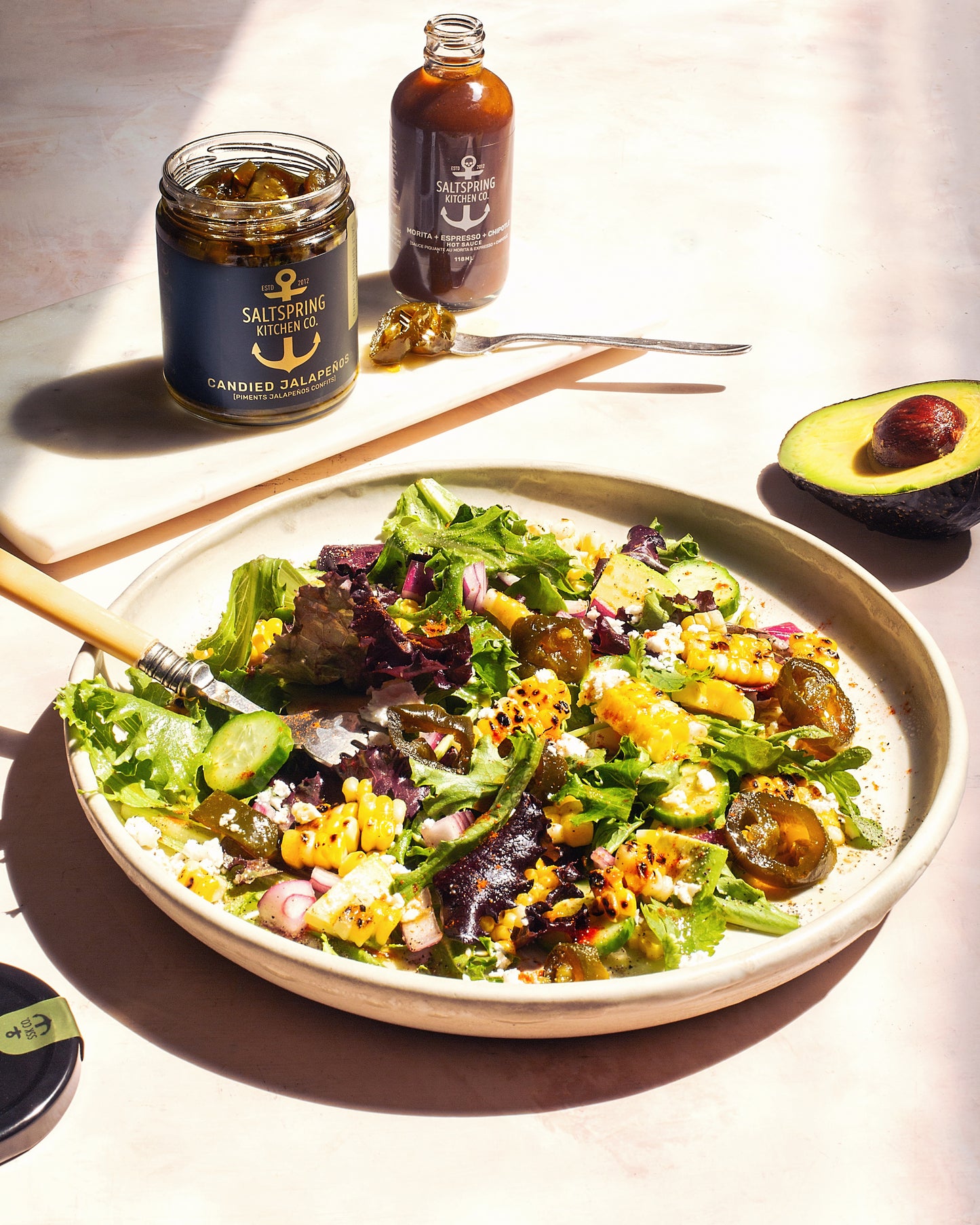 Saltspring Kitchen Company Mexican Corn Salad on a plate with candied jalapenos and morita hot sauce in the background