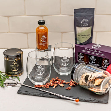 Salt Spring Kitchen Company Happy Hour Gourmet Gift Box contents on the counter with jars and glasses