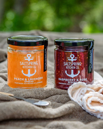 SaltSpring Kitchen Company Peach and Lavender and Raspberry and Rose jam jars outside on a blanket with a tulip