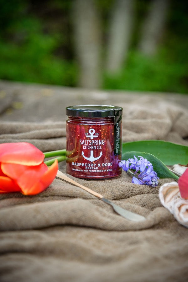 SaltSpring Kitchen Company Raspberry and Rose Gourmet Fruit Spread outside with flowers on a blanket