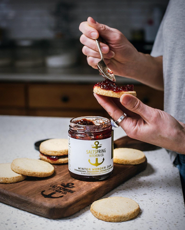 Salt Spring Kitchen Company Winter Wonder Jam jar on the counter with a person making Linzer cookies