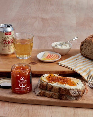 SaltSpring_Kitchen_Company_Peach_and_Lavender_Spread_on_soft_cheese_and_sourdough_with_a_cider_on_a_table