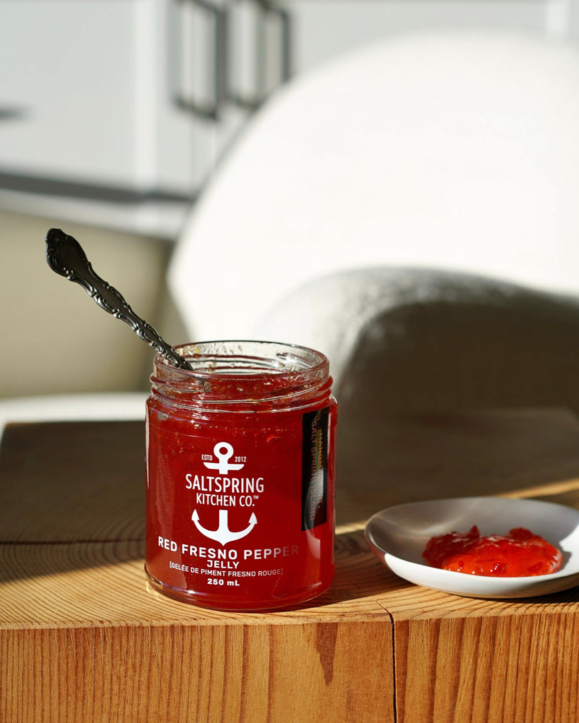Red Fresno Pepper Jelly on a side table with a small dish of jelly