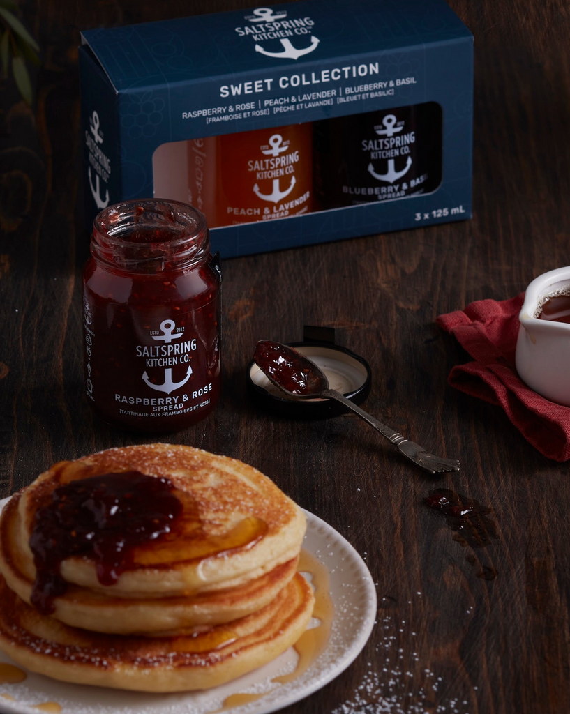 Stack of pancakes with syrup,, and a box of Sweet Collection on a wooden table.