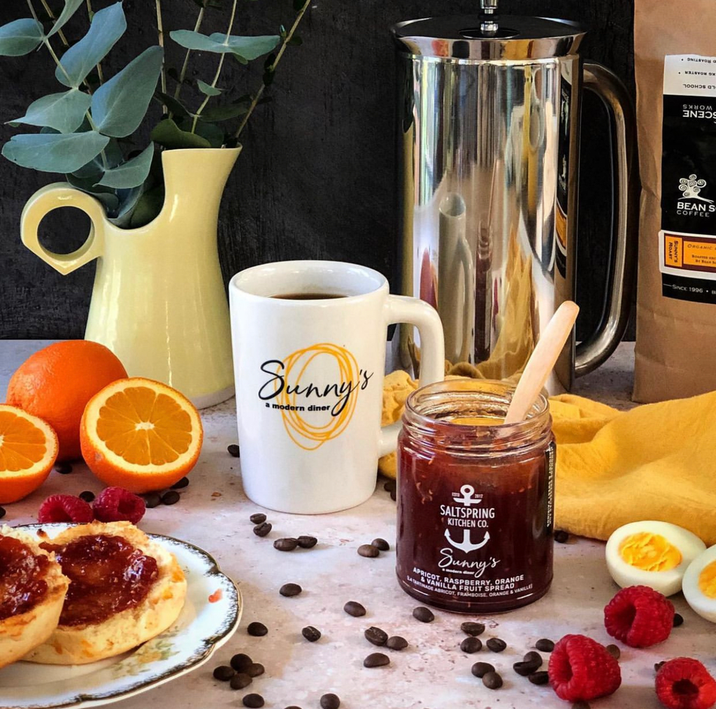 Salt Spring Kitchen Company Sunny's Apricot, Raspberry, Orange & Vanilla Fruit Spread with English muffins and a coffee on a table