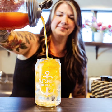Salt Spring Kitchen Company Melanie Mulherin pouring a drink into a branded beer can glass