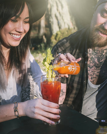 Salt Spring Kitchen Company Habanero Curry and Orange Hot Sauce being added to a cocktail with friends