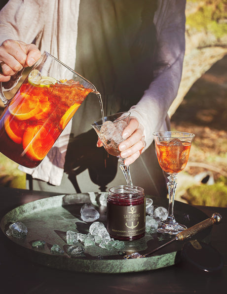 Salt Spring Kitchen Company Sour Cherry, Rhubarb and Rosemary Spread with pitcher of drinks and summer scene
